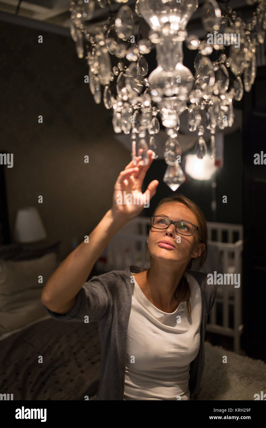 Jolie jeune femme choisir le bon lustre pour son appartement dans une boutique d'accessoires de maison moderne aux tons de couleur peu profondes de l'image (DOF) Banque D'Images