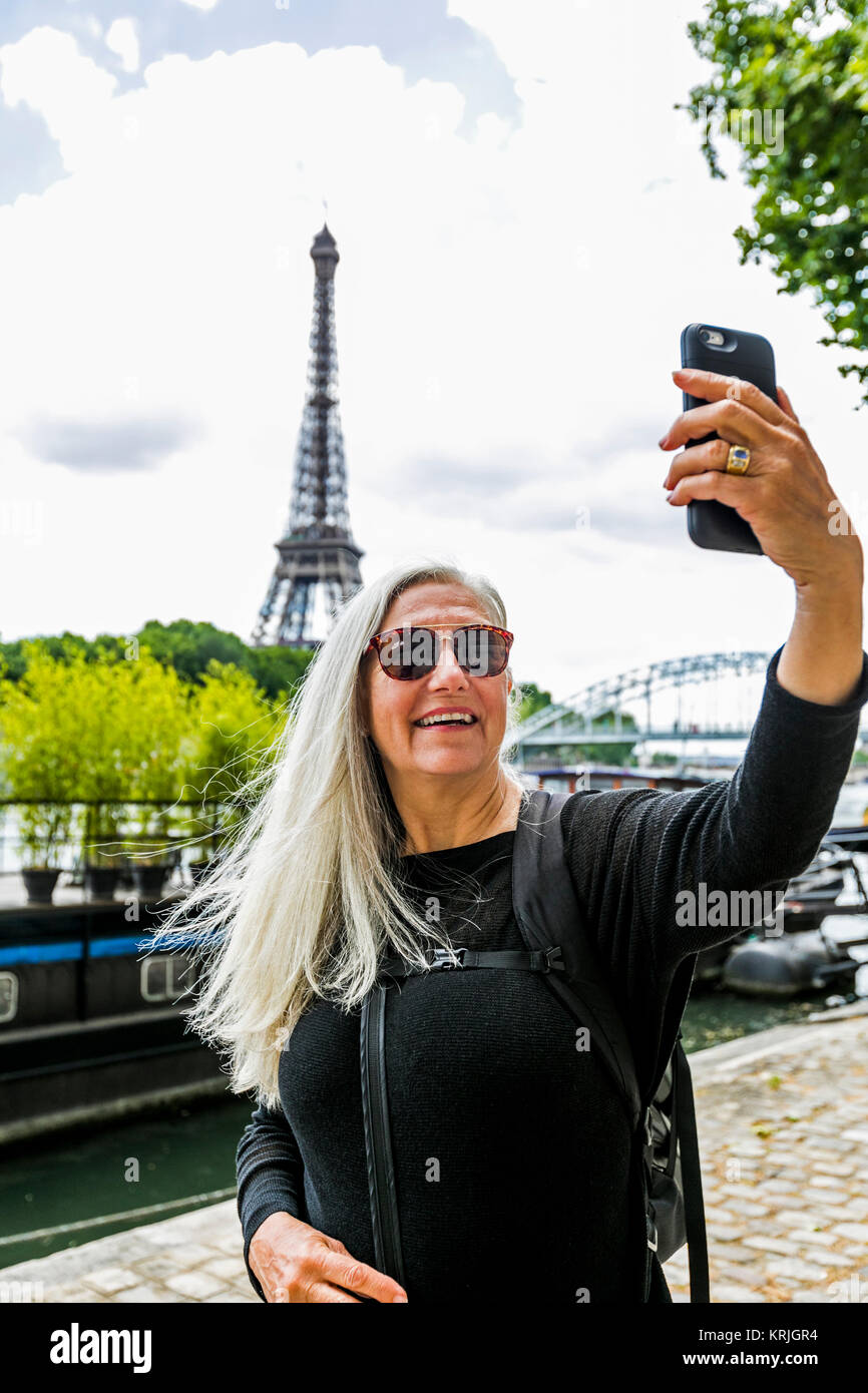Caucasian woman posing for selfies téléphone cellulaire près de Eiffel Tower Banque D'Images