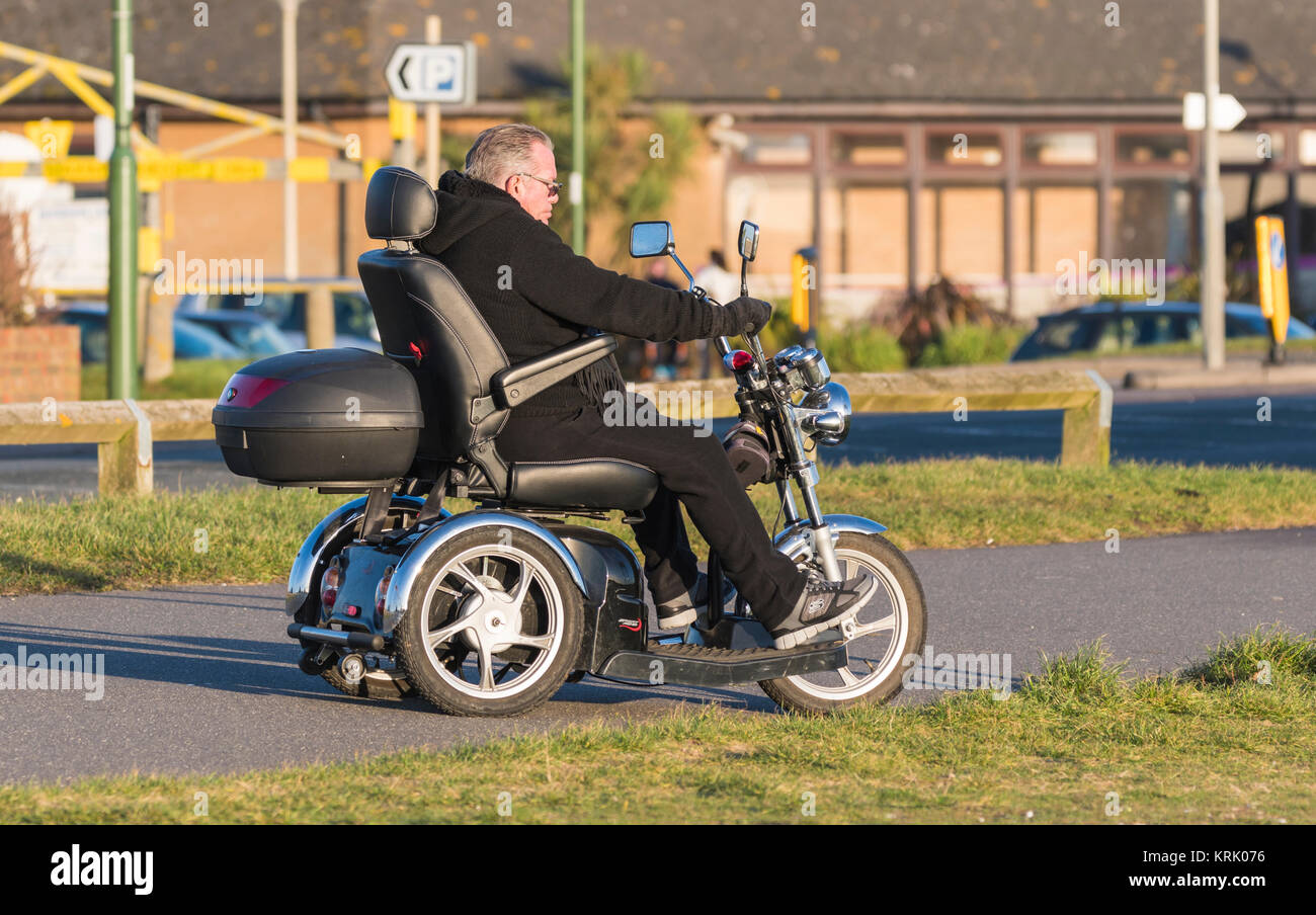 Un homme monté sur 3 roues scooter de mobilité Mobilité électrique au Royaume-Uni. Banque D'Images