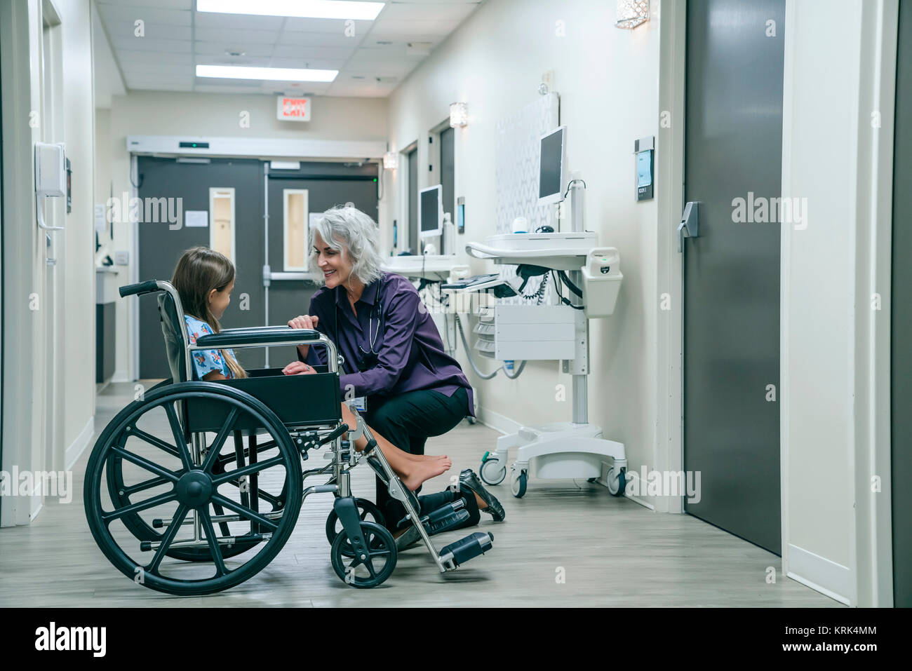 Smiling doctor réconfortant girl in wheelchair Banque D'Images