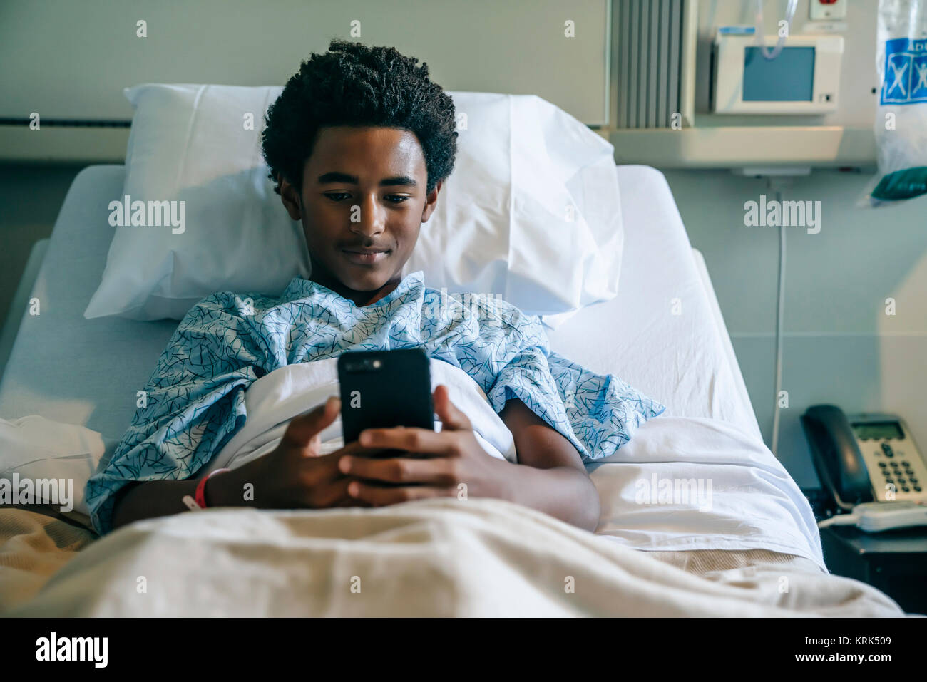 Tableau noir texting on cell phone in hospital bed Banque D'Images