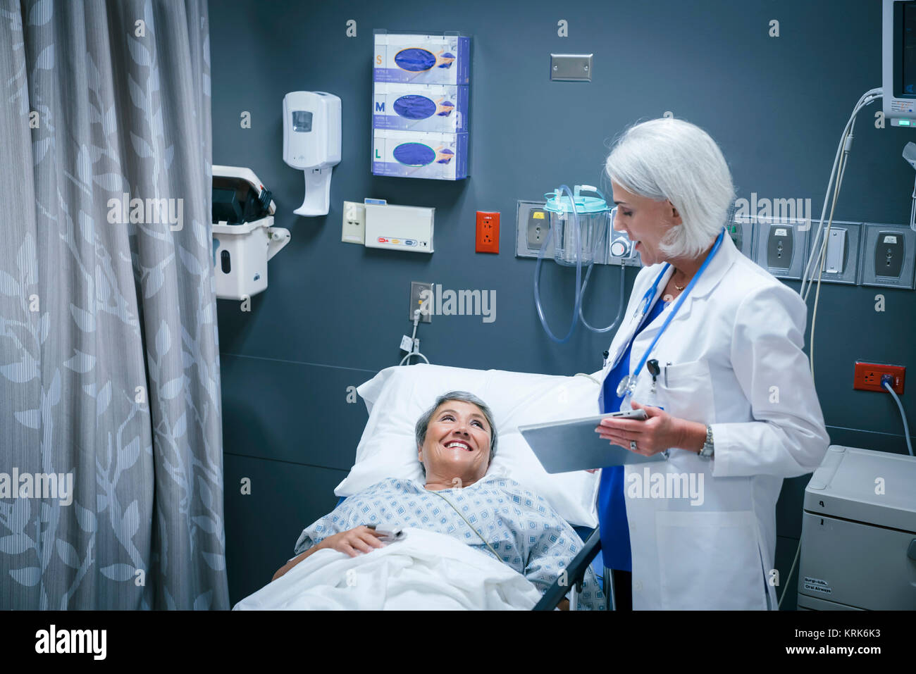 Médecin with digital tablet talking to patient smiling in hospital Banque D'Images