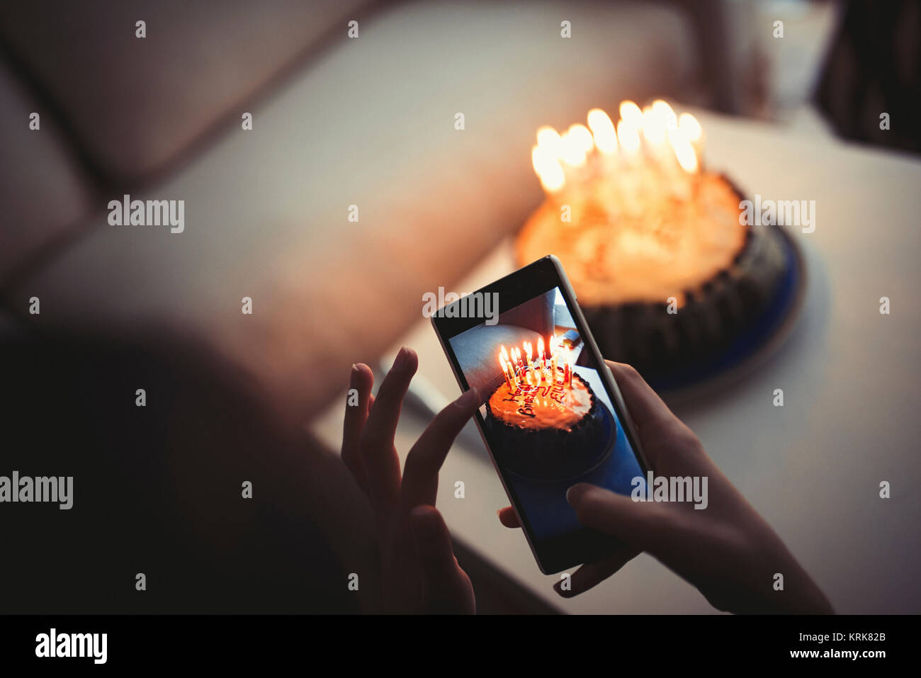Mixed Race girl photographing birthday cake with cell phone Banque D'Images