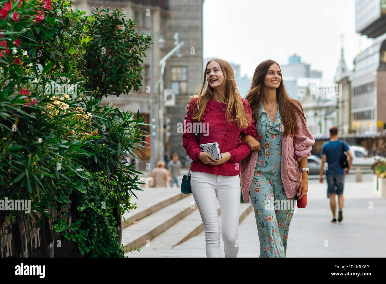 Smiling Caucasian women walking arm in arm en ville Banque D'Images
