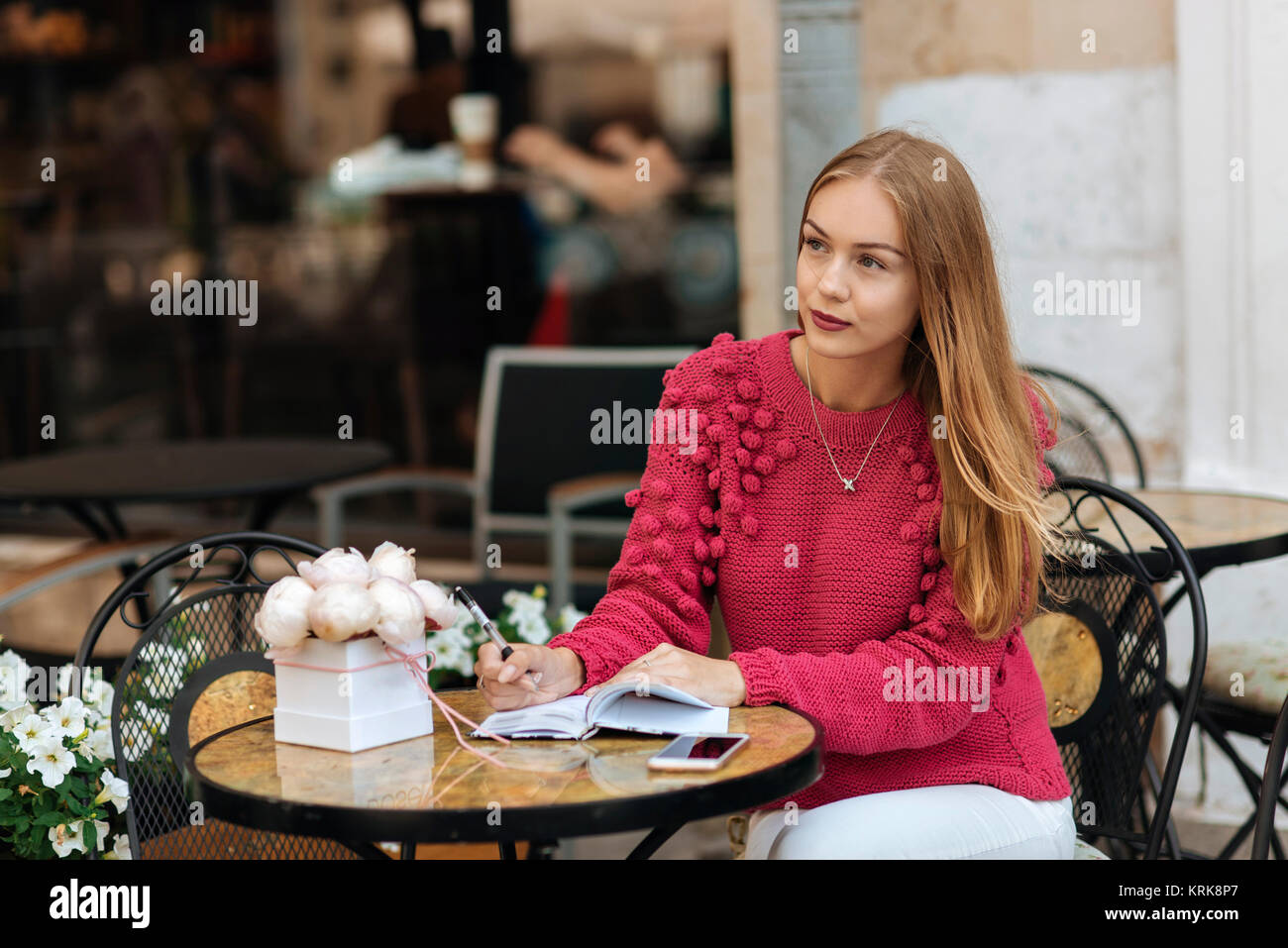 Caucasian woman sitting at table écrit dans le journal Banque D'Images