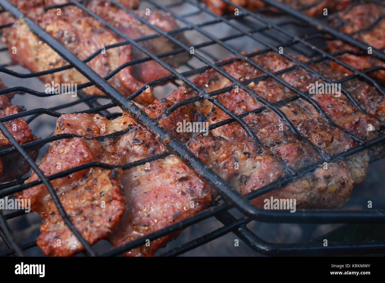Sur une belle journée d'été, les gens faire griller de la viande sur un barbecue. La viande est presque prêt, il est déjà doré et recouvert d'une fine croûte délicieux. Banque D'Images