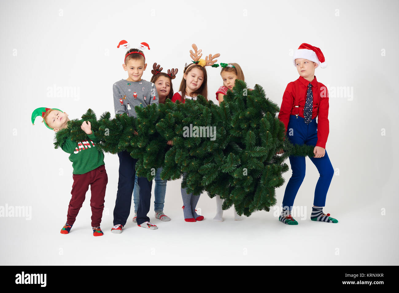 Groupe d'enfants essayer de soulever l'arbre de Noël Banque D'Images