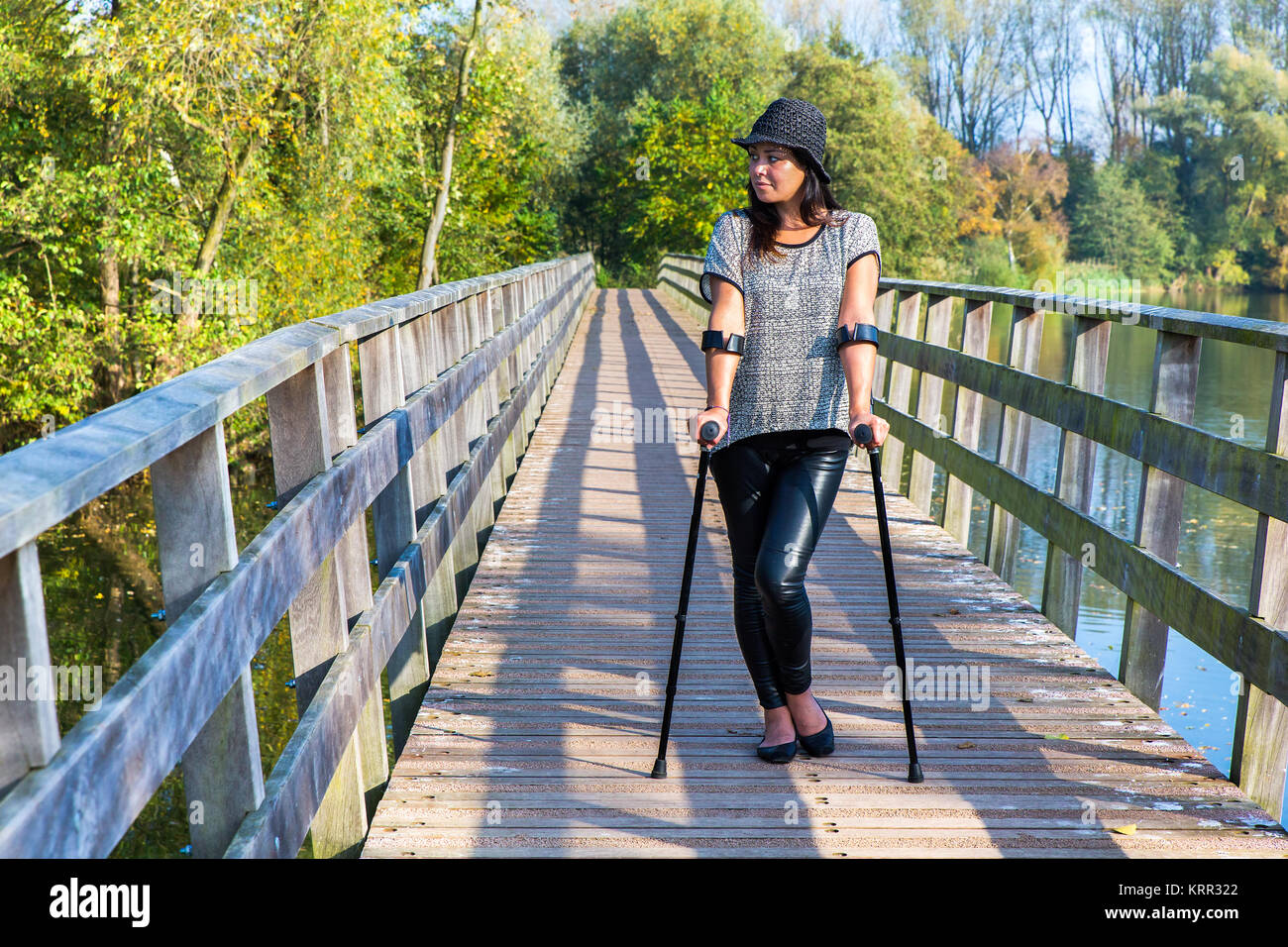 Jeune femme marchant avec des béquilles sur le pont en bois Banque D'Images