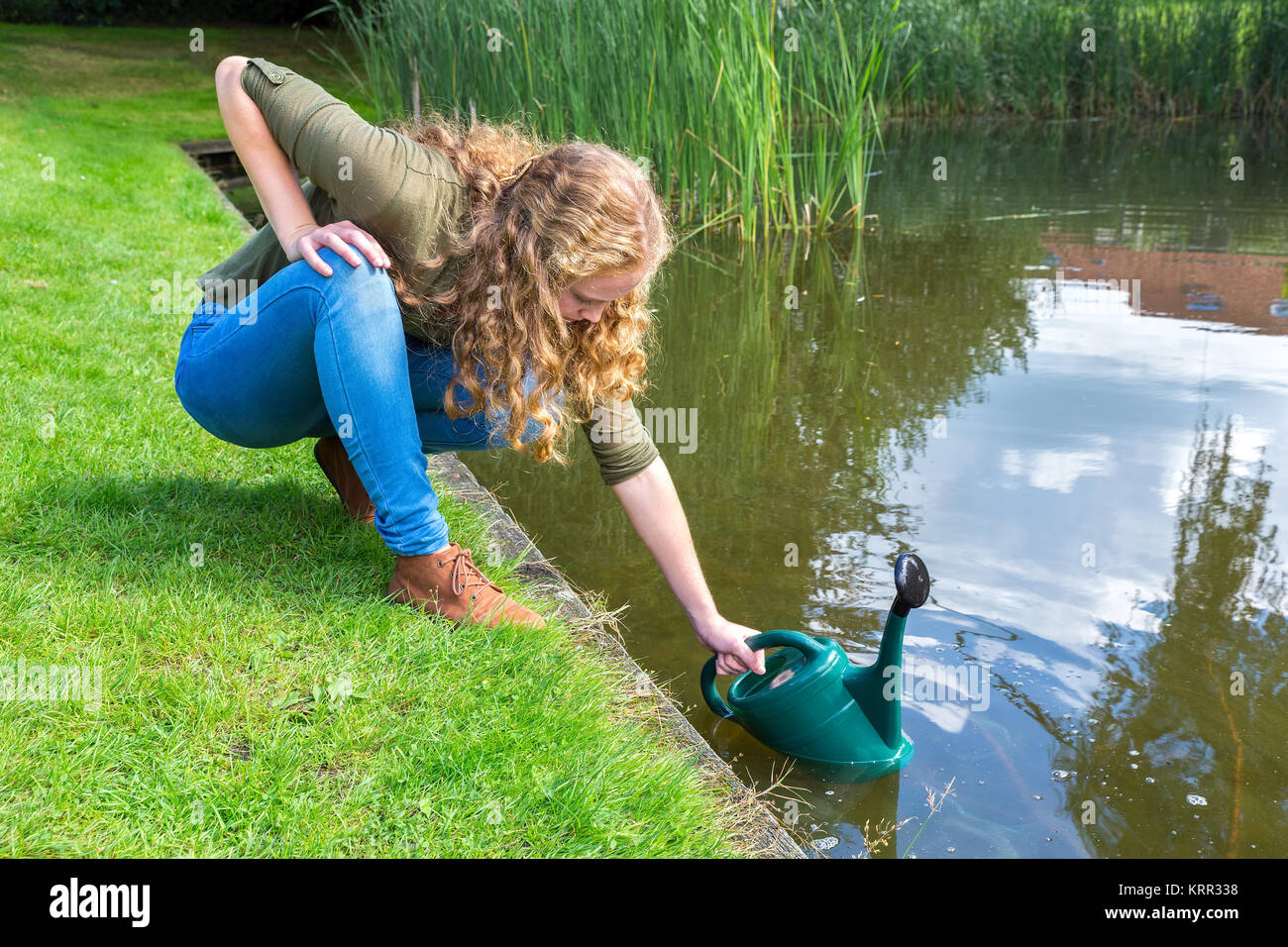 Jeune femme néerlandaise roulette vert remplissage avec de l'eau dans la nature Banque D'Images