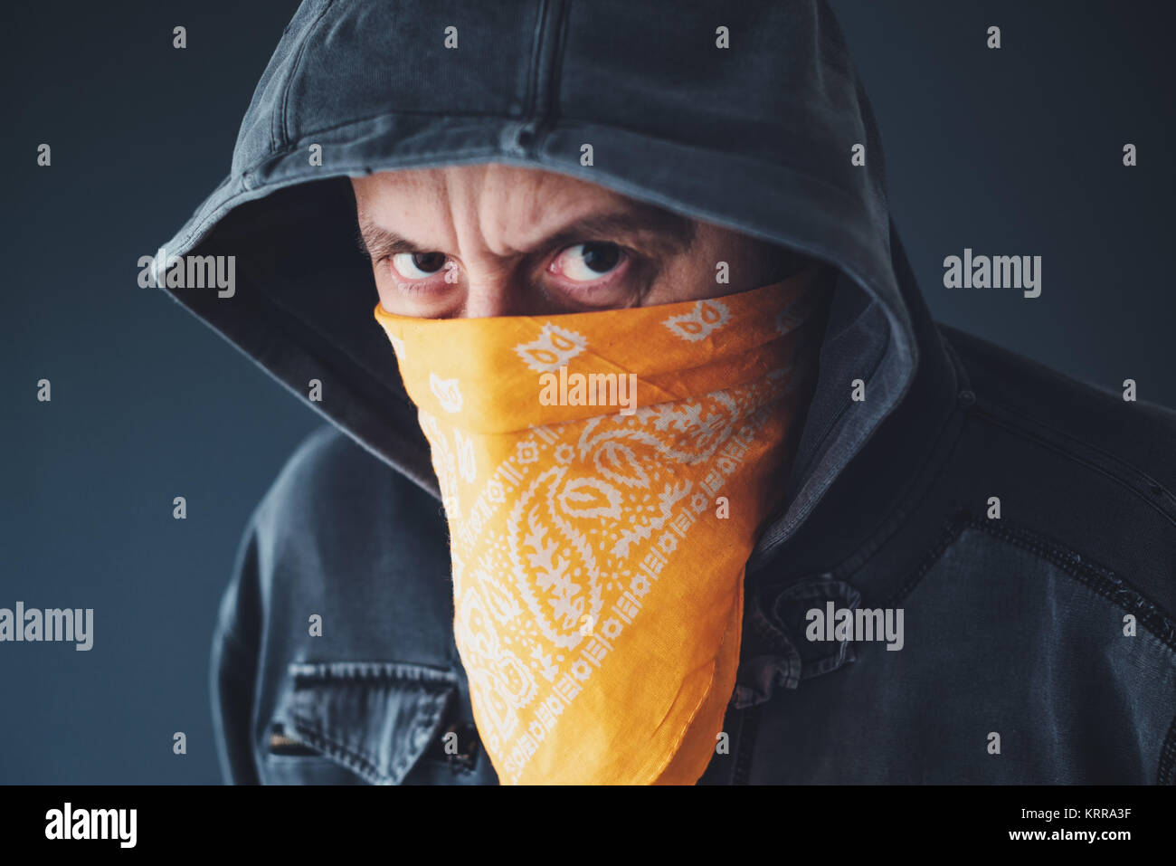 Membre de gang à capuchon avec écharpe sur le visage criminel looking at camera Banque D'Images