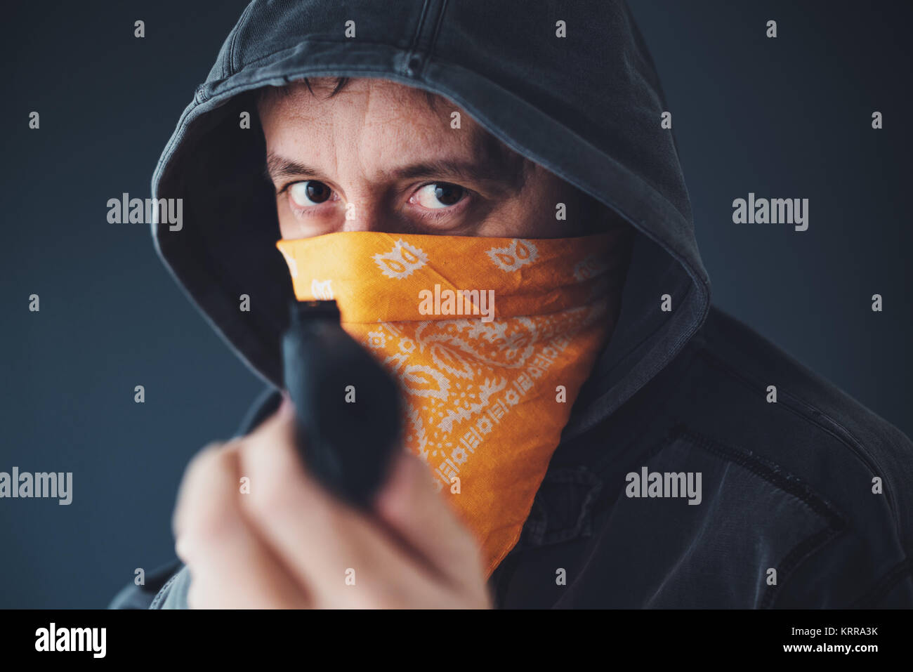 Membre de gang à capuchon avec écharpe sur le visage criminel braquer une arme Banque D'Images