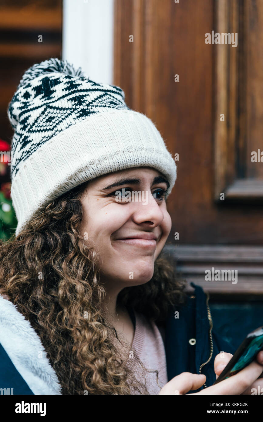Teenage girl in Knit hat avec l'expression du visage étrange sms wifi Banque D'Images