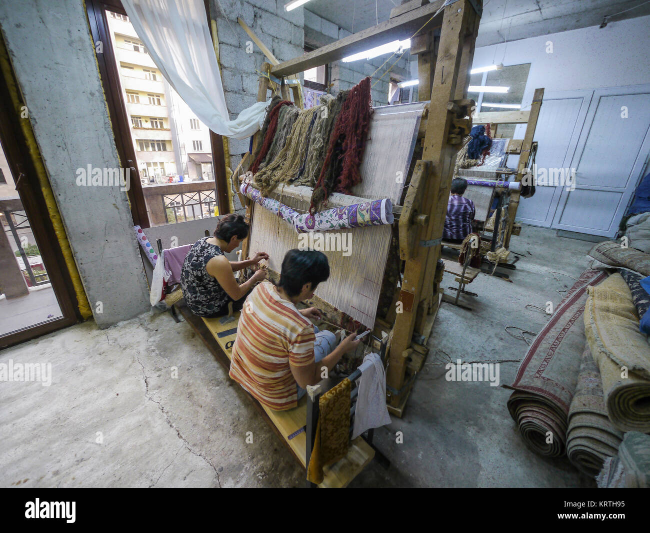 Atelier de tapis de l'Arménie, Erevan, Arménie, octobre 2012 : les femmes tissent dans un vieux métier à tisser en bois tapis traditionnel arménien. Banque D'Images