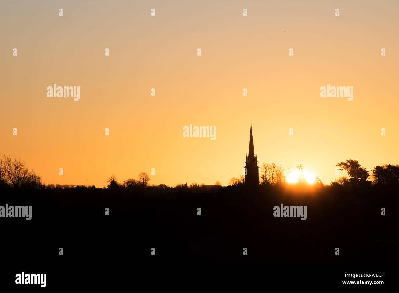 Lever du soleil derrière un clocher d'église en décembre. Rois Sutton, Nr Banbury, Northamptonshire, en Angleterre. Silhouette Banque D'Images