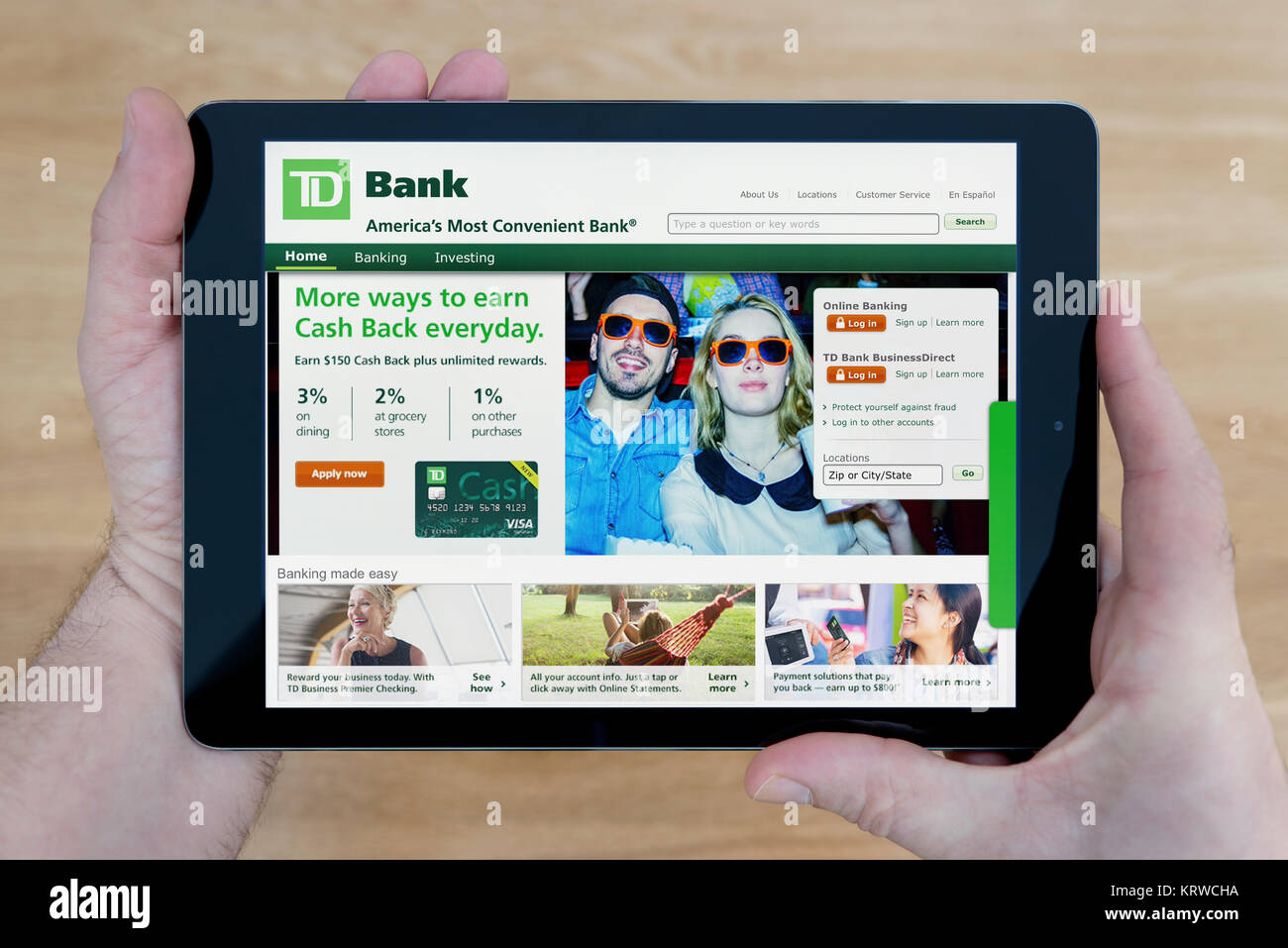 Un homme regarde le site web de la Banque TD sur son iPad tablet device, tourné contre une table en bois page contexte (usage éditorial uniquement) Banque D'Images