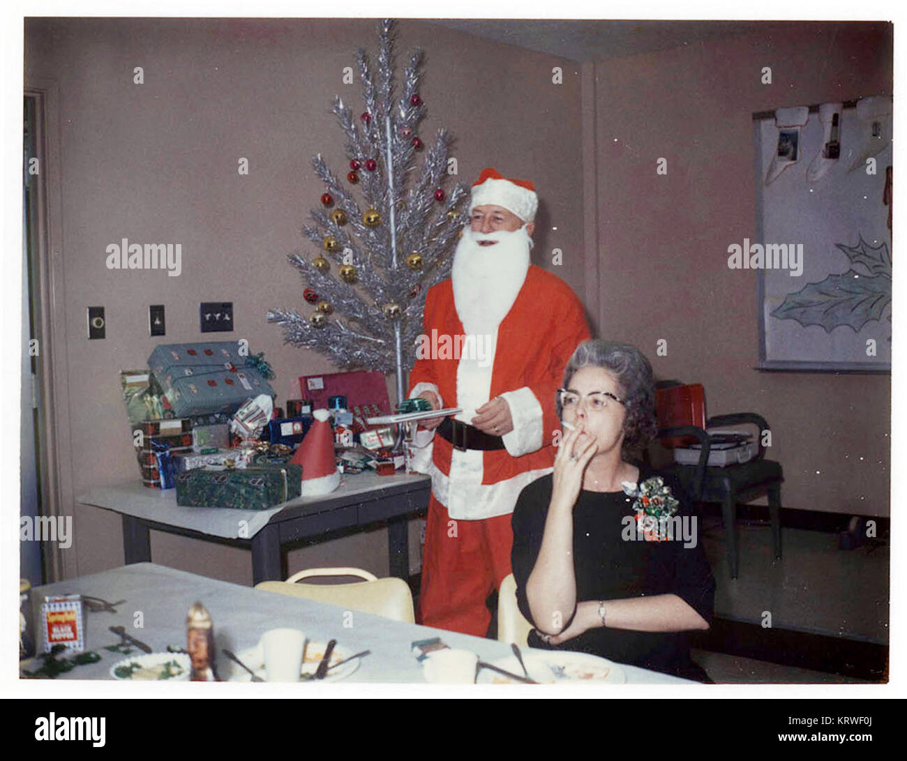 Deux personnes sur la photo à un party de bureau de Noël au milieu des années 60 (1965) L'un habillé en père Noël et l'autre fume une cigarette Banque D'Images