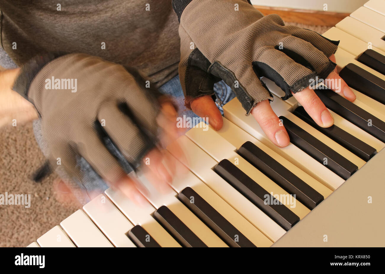 Un pianiste se bat le froid de l'hiver en jouant avec des gants sans doigts. Une main touche une corde sensible, tandis que l'autre joue rapidement. Banque D'Images