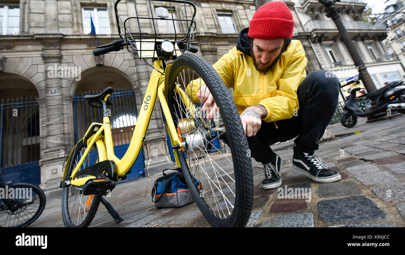 Paris, France. Déc 20, 2017. Le réparateur Yoann Andrieux répare un vélo Ofo dans Paris, France, le 20 décembre, 2017. Deux semaines après son lancement ici, l'un des systèmes de partage de vélos populaires, Ofo, vise le leadership dans le marché en croissance rapide comme la ville s'efforce de promouvoir le transport vert pour réduire les émissions. La signature de l'entreprise vélo jaune vif peut être trouvé à la fois tranquille et venez visiter des coins de rue autour de la ville, et gagnent rapidement en popularité parmi les habitants et les touristes. Crédit : Chen Yichen/Xinhua/Alamy Live News Banque D'Images