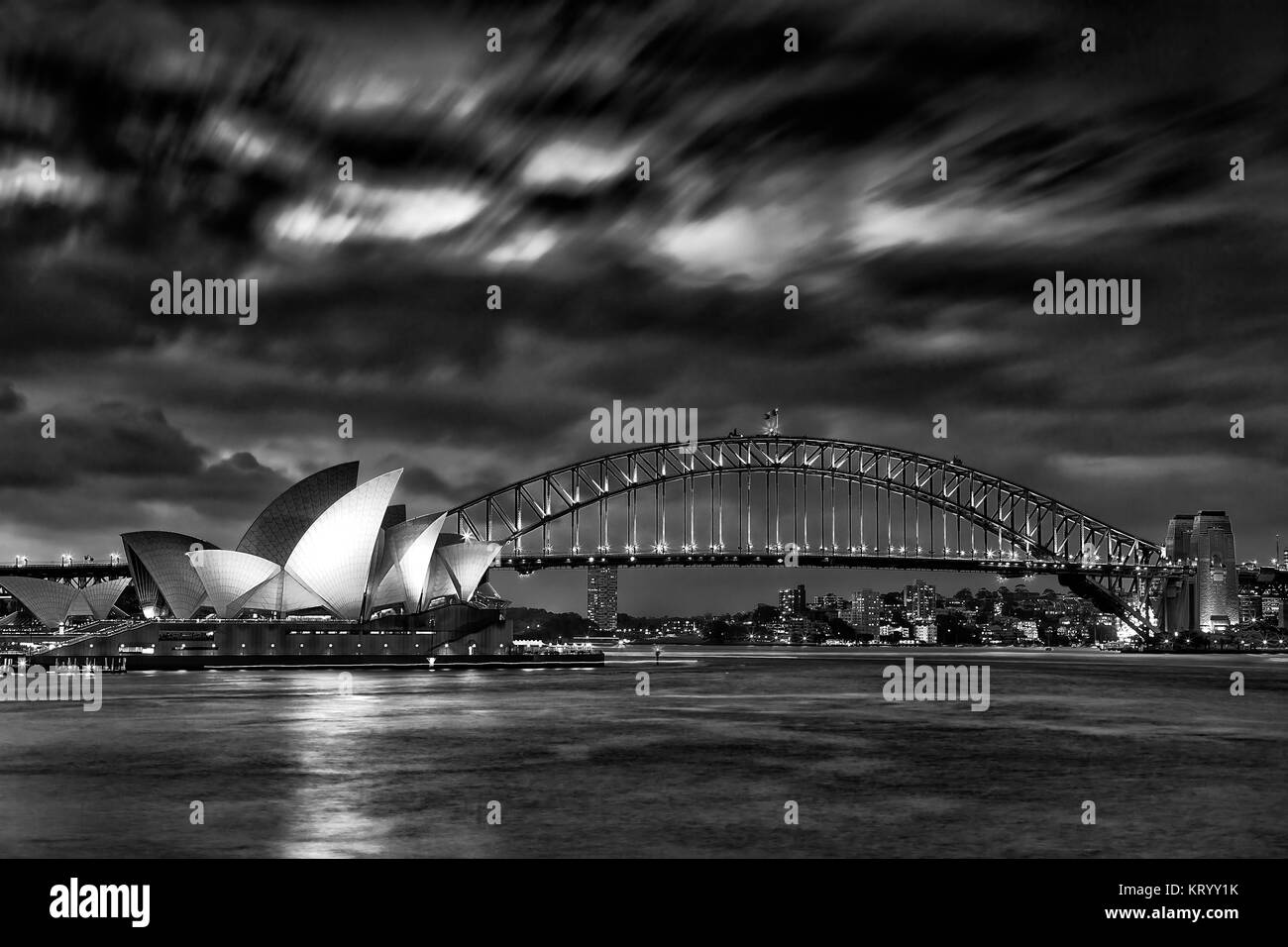 Sydney, Australie, 18 mars 2017 : célèbre Opéra de Sydney et le Harbour Bridge au coucher du soleil. Les nuages et les Lumières floues de repères reflètent dans blur Banque D'Images