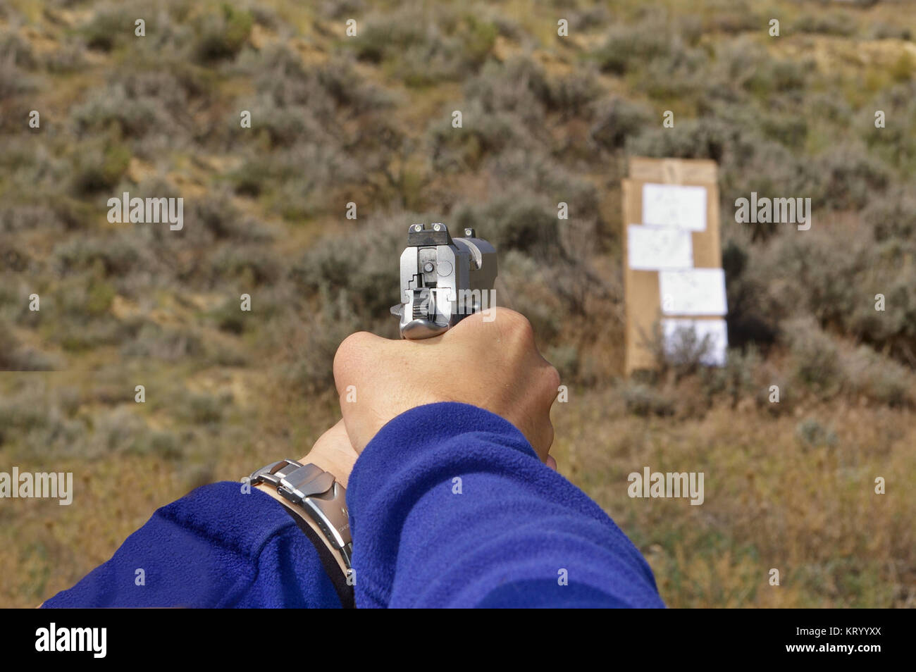 1911-type pistolet semi-automatique dans une main courante visant à un carton/papier cible sur une plage en plein air Banque D'Images