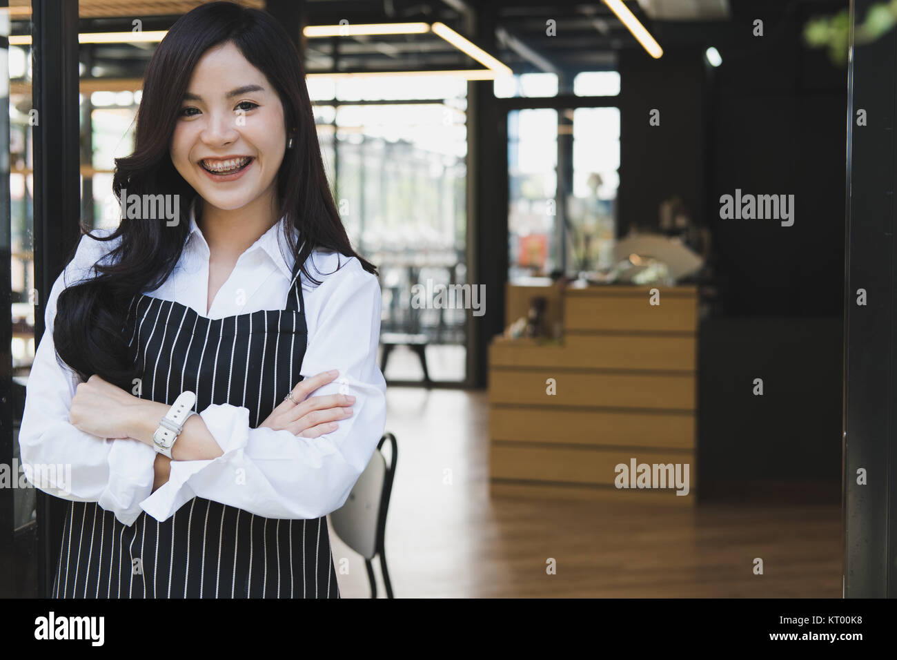 Propriétaire de petite entreprise debout avec les bras croisés au café. asian female barista portant un tablier smiling at cafe. food service, concept de restaurant. Banque D'Images
