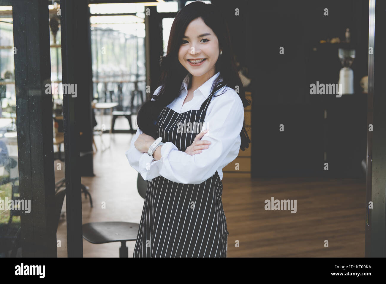 Propriétaire de petite entreprise debout avec les bras croisés au café. asian female barista portant un tablier smiling at cafe. food service, concept de restaurant. Banque D'Images