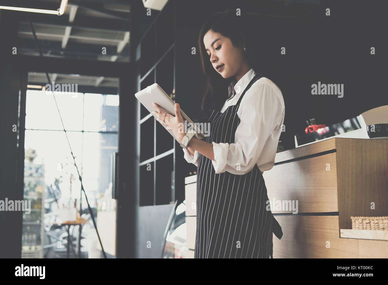 Propriétaire de petite entreprise holding tablet in coffee shop. asian female barista de porter un tablier à l'aide au touchpad dans bar cafe. service alimentaire, restaur Banque D'Images