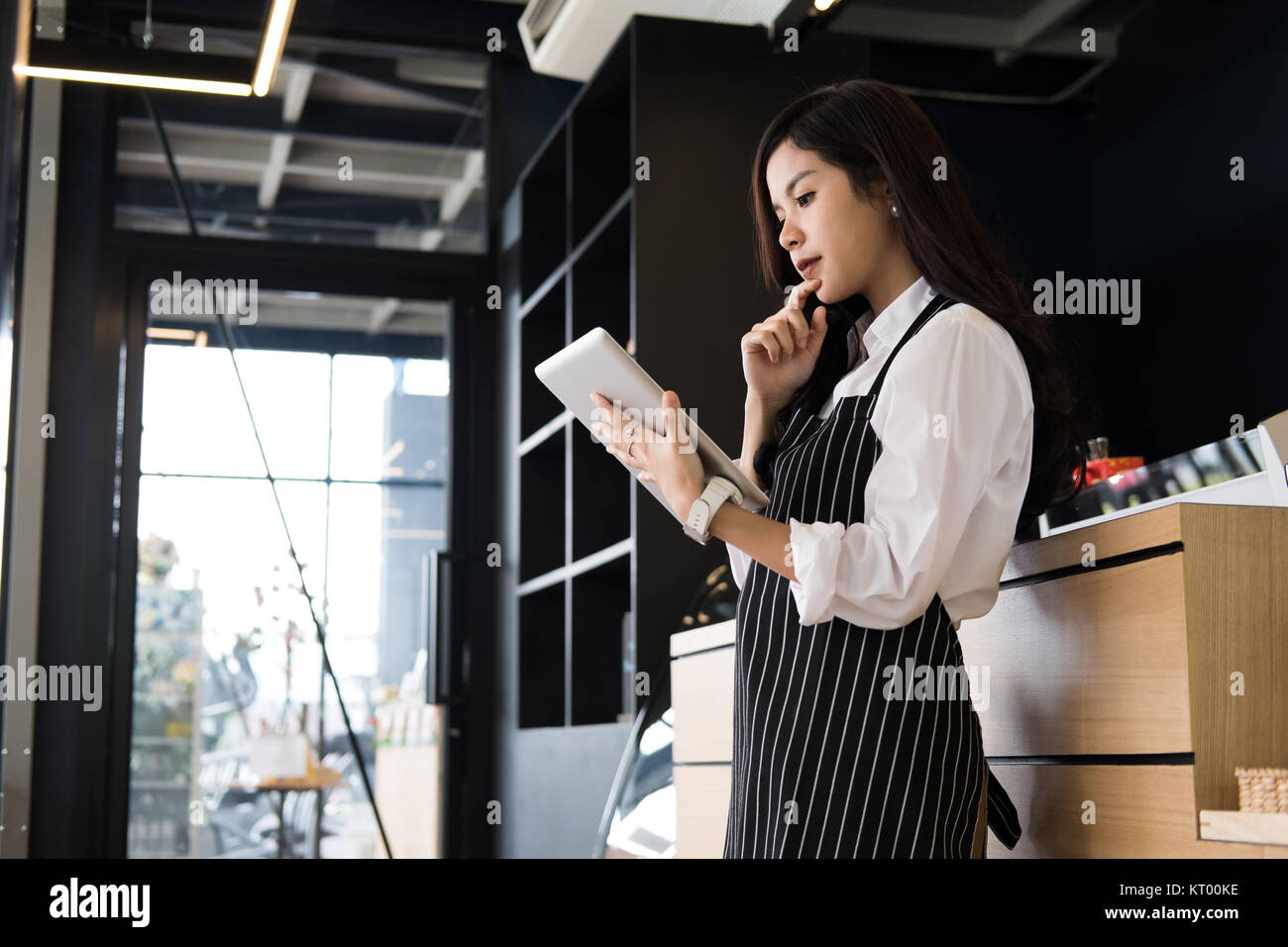 Propriétaire de petite entreprise holding tablet in coffee shop. asian female barista de porter un tablier à l'aide au touchpad dans bar cafe. service alimentaire, restaur Banque D'Images