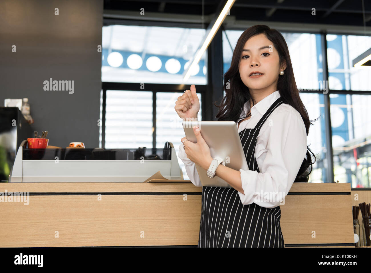Propriétaire de petite entreprise holding tablet in coffee shop. asian female barista de porter un tablier à l'aide au touchpad dans bar cafe. service alimentaire, restaur Banque D'Images