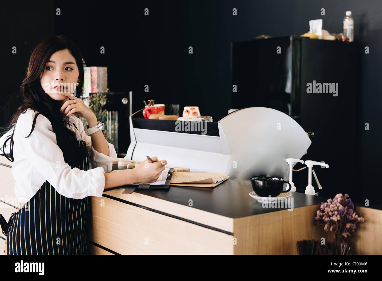 Propriétaire de petite entreprise avec compteur à l'ordinateur portable dans un café. asian female barista portant un tablier écrit remarque au bar en café, restaurant service alimentaire. Banque D'Images
