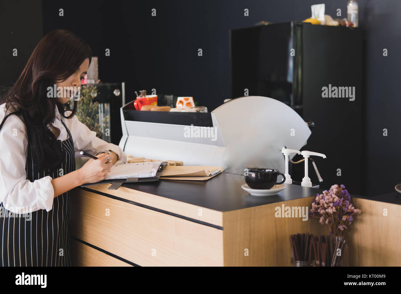 Propriétaire de petite entreprise avec compteur à l'ordinateur portable dans un café. asian female barista portant un tablier écrit remarque au bar en café, restaurant service alimentaire. Banque D'Images