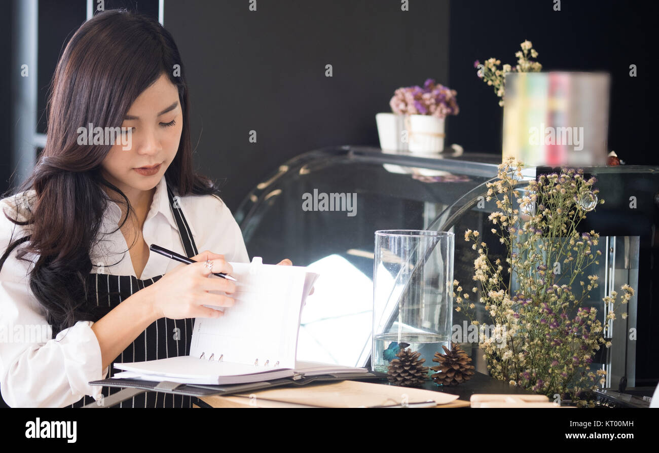 Propriétaire de petite entreprise avec compteur à l'ordinateur portable dans un café. asian female barista de porter un tablier à bar dans le café. food service, restaurant, entrepreneu Banque D'Images