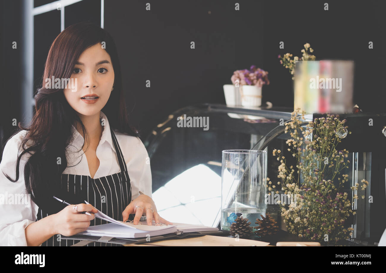 Propriétaire de petite entreprise avec compteur à l'ordinateur portable dans un café. asian female barista de porter un tablier à bar dans le café. food service, restaurant, entrepreneu Banque D'Images