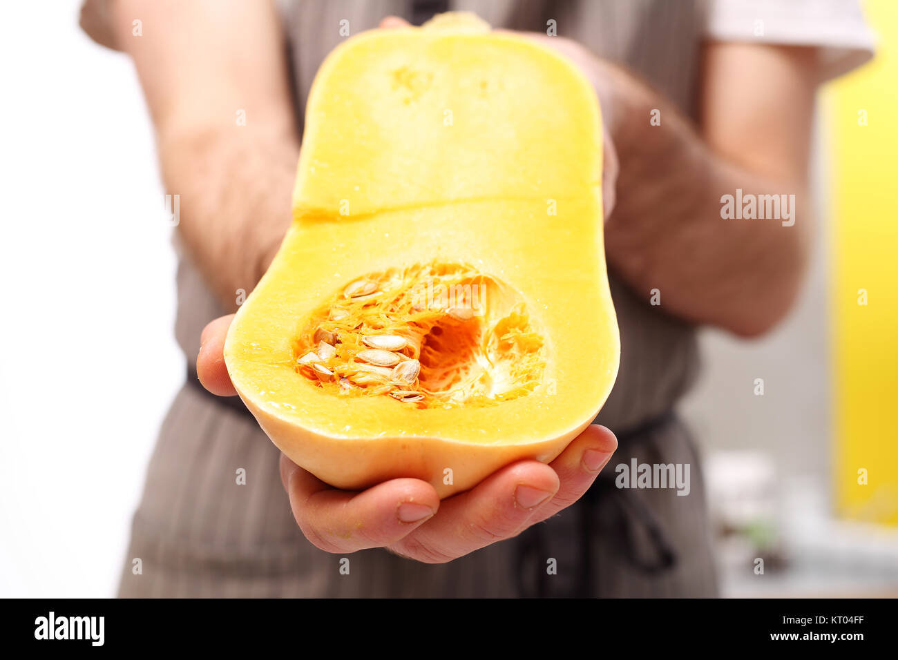 Courge butternut dans un végétalien. le cuisinier tient dans ses mains la moitié d'une citrouille. Banque D'Images