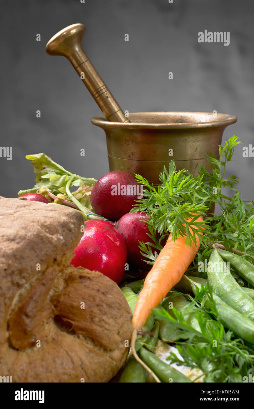 Légumes frais savoureux et croustillant du pain fait maison avec de vieux mortier en bronze. Banque D'Images