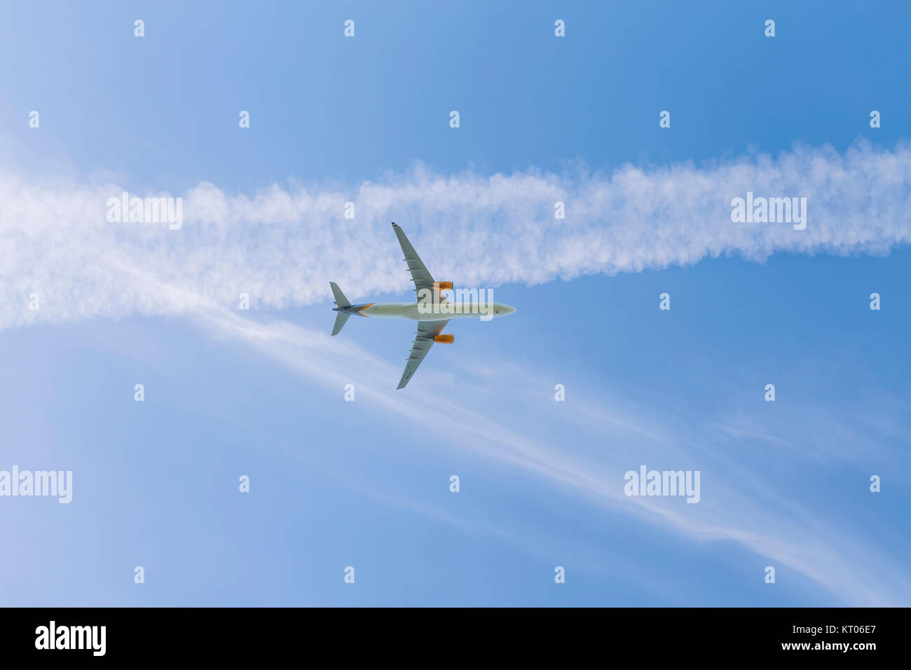 Un avion à réaction volant au-dessus d'un ciel bleu avec des traînées de vapeur Banque D'Images