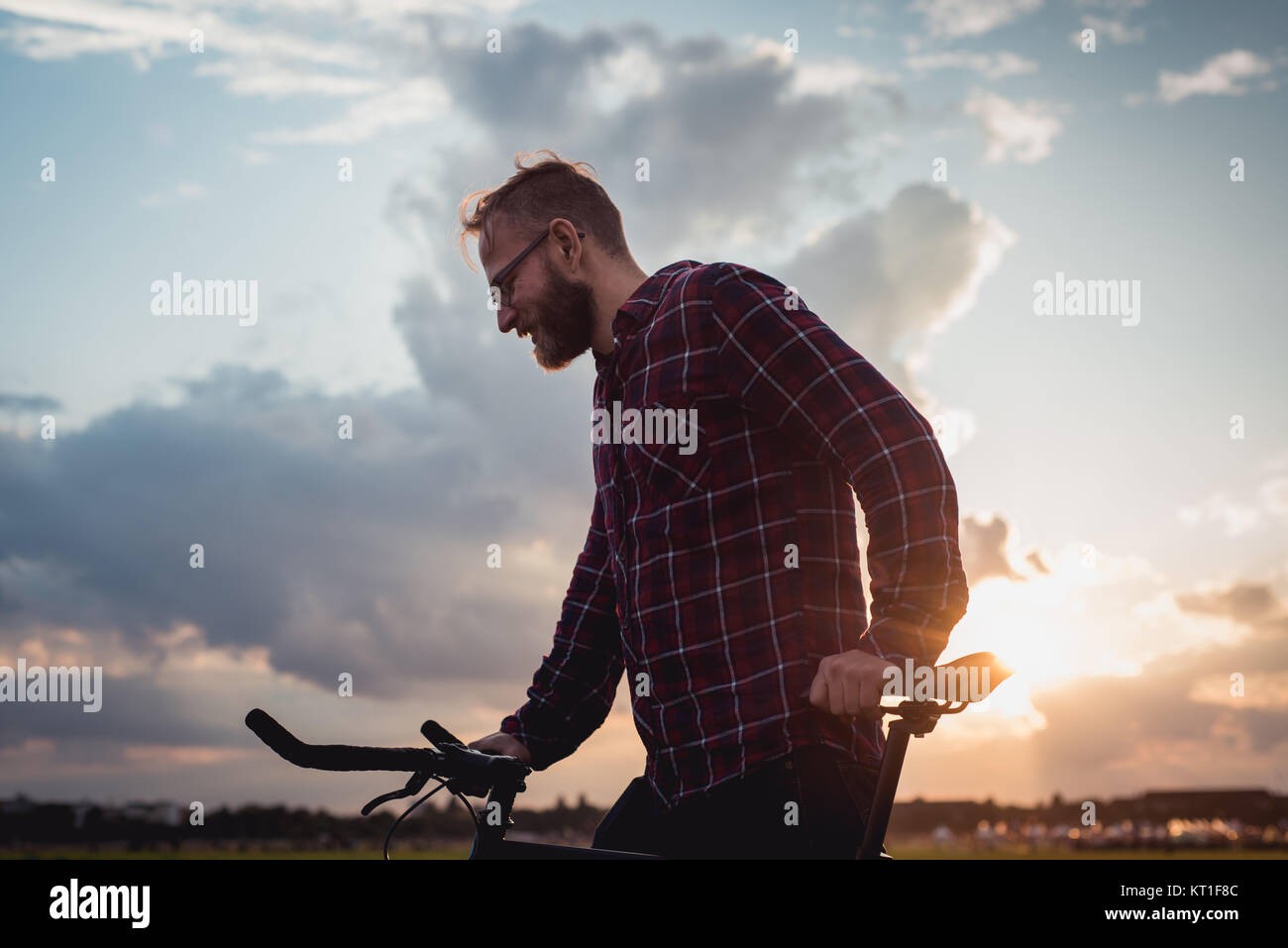35 ans homme hipster avec son vélo au champ Templehof à Berlin, Allemagne bénéficiant d'un beau coucher du soleil. Banque D'Images