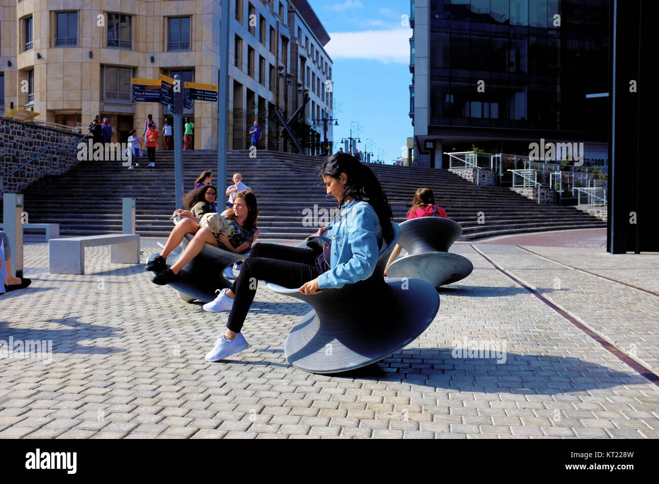 Les femmes tournent autour sur des chaises à l'extérieur de la filature wobbly Zeitz Mocaa art museum à Cape Town, Afrique du Sud Banque D'Images