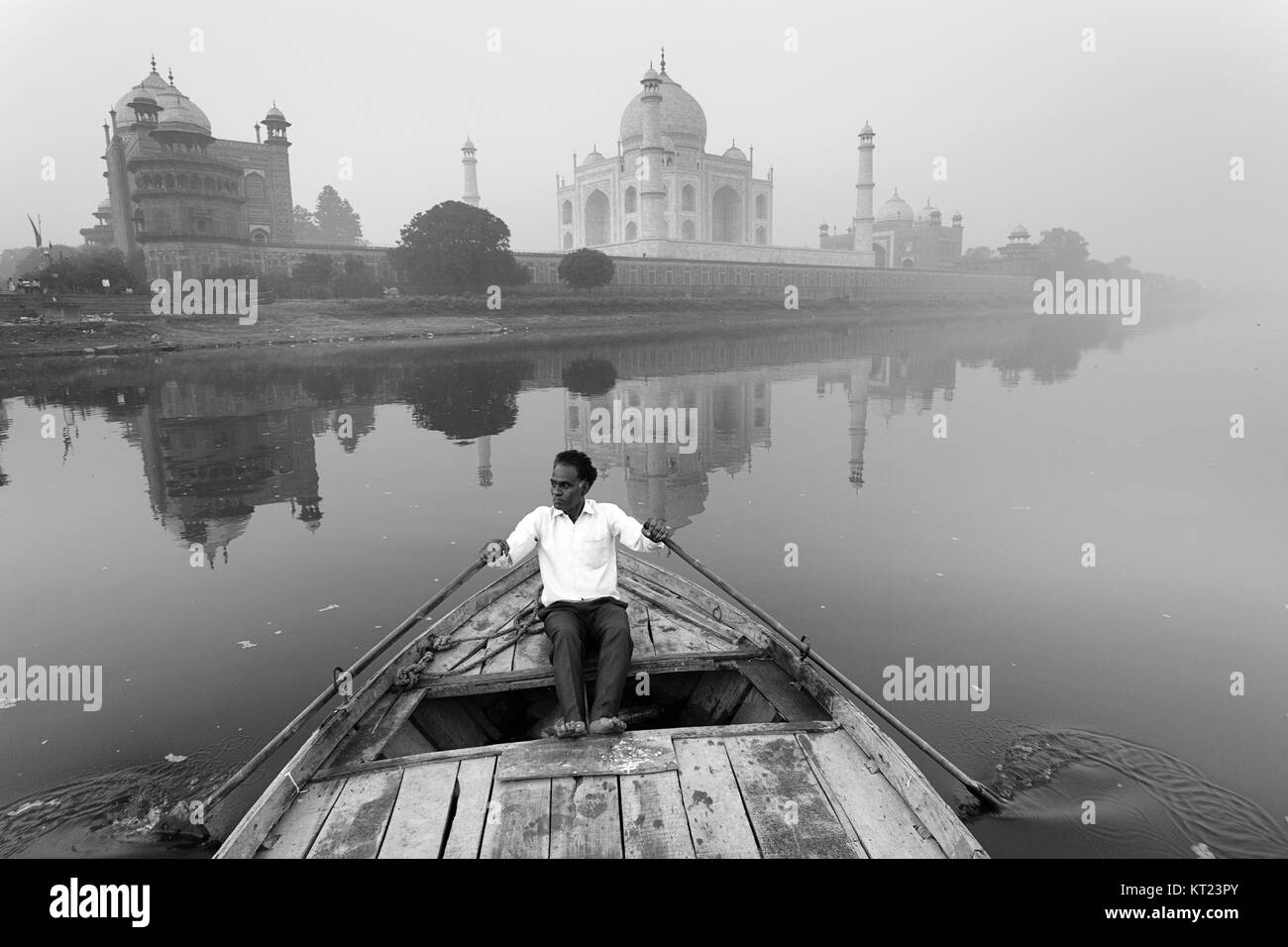 Indian man paddling en bateau traditionnel en bois sur la rivière Yamuna avec Taj Mahal à l'arrière et c'est reflet dans l'eau, Agra, Uttar Pradesh, Inde Banque D'Images