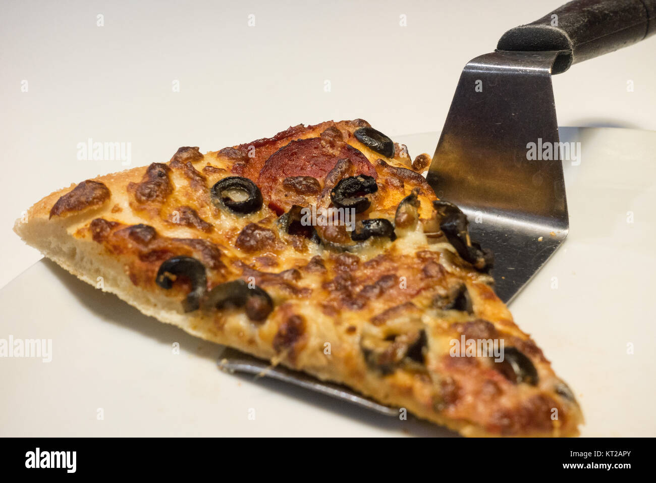 Pizza Slice mixtes servant à l'aide d'une spatule sur la plaque blanche Banque D'Images