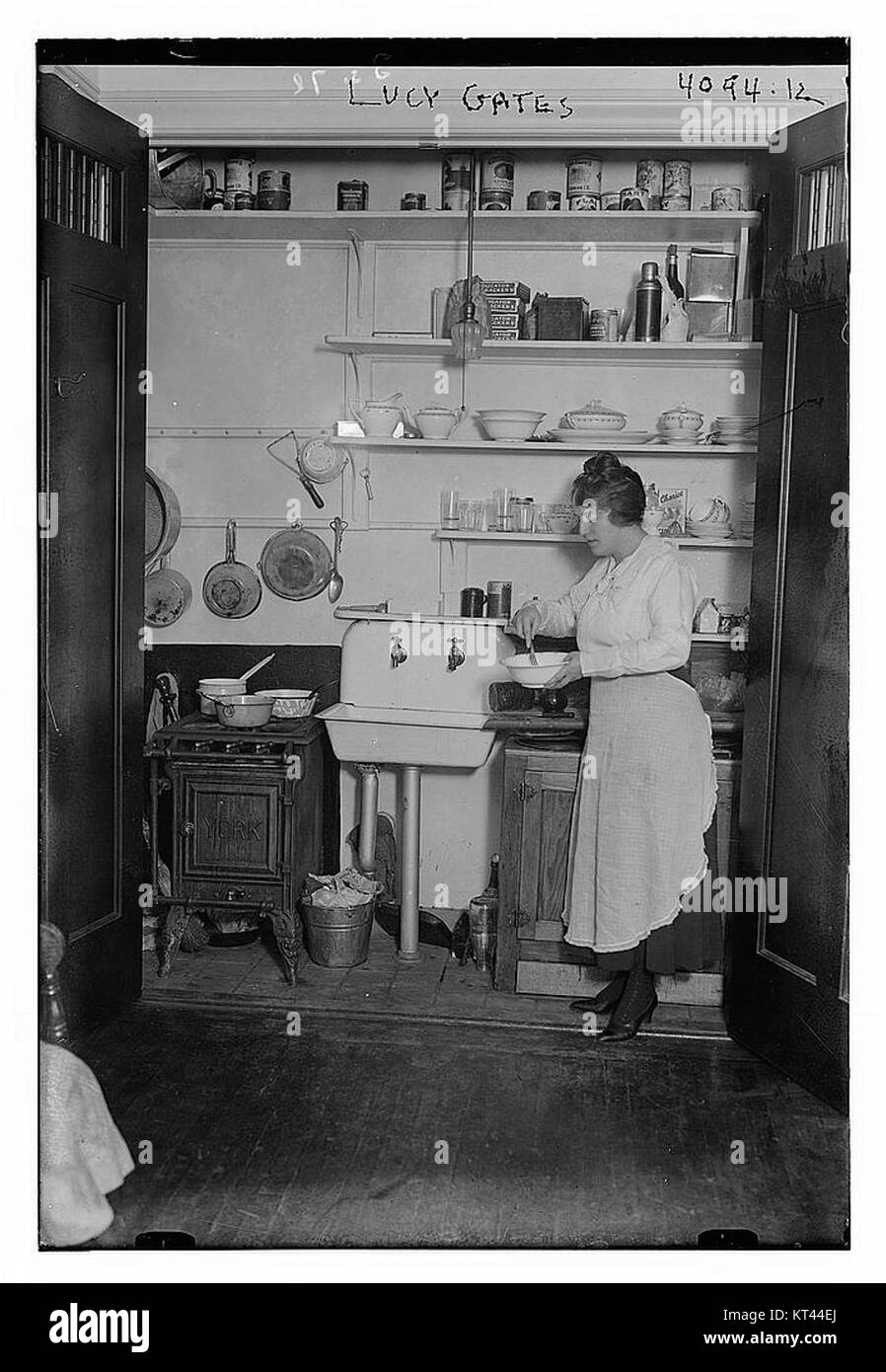 Cette photographie capture Lucy Gates dans une cuisine domestique. Il dépeint la vie quotidienne d'un individu, en se concentrant sur la normalité et les moments personnels de l'époque, offrant un aperçu de la vie américaine du milieu du XXe siècle. Banque D'Images