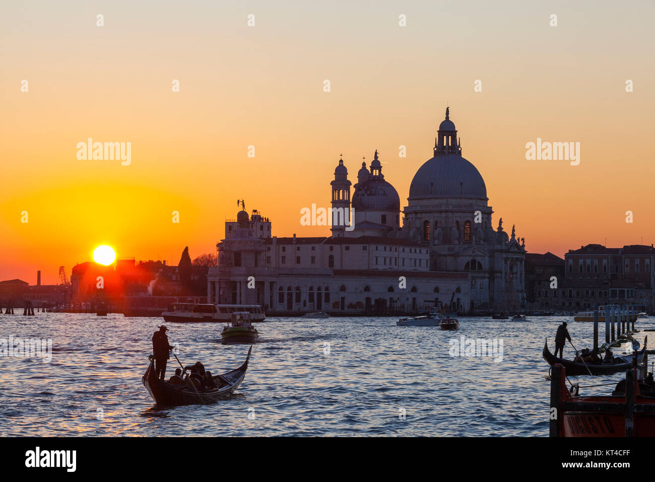 Orange Couleur coucher de soleil sur la lagune de Venise et la Basilique Santa Maria della Salute avec gondoles avec les touristes dans ta scène romantique Banque D'Images