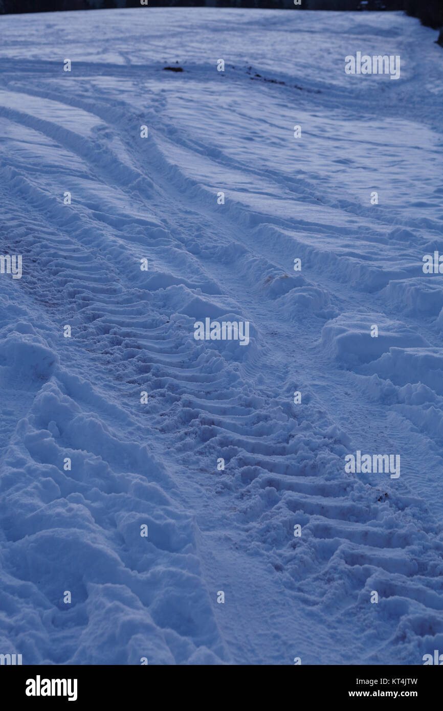 Certaines marques de dérapage conduirait dans un snowscape au point de l'heure bleue en soirée. Banque D'Images