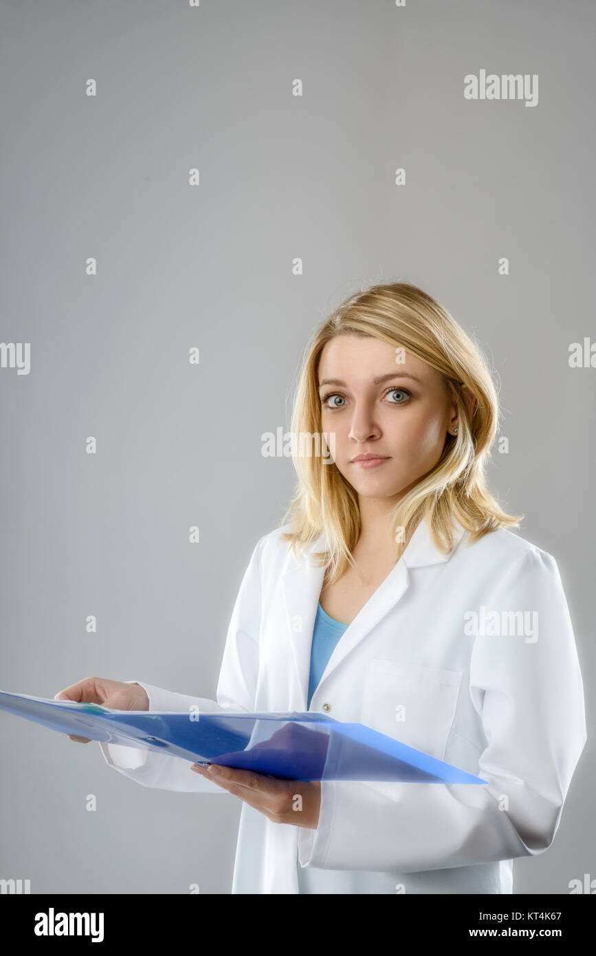 Portrait d'une jeune femme énergique, un scientifique ou un étudiant en technologie avec des notes dans un dossier bleu sur fond gris. L'espace pour votre texte. Banque D'Images