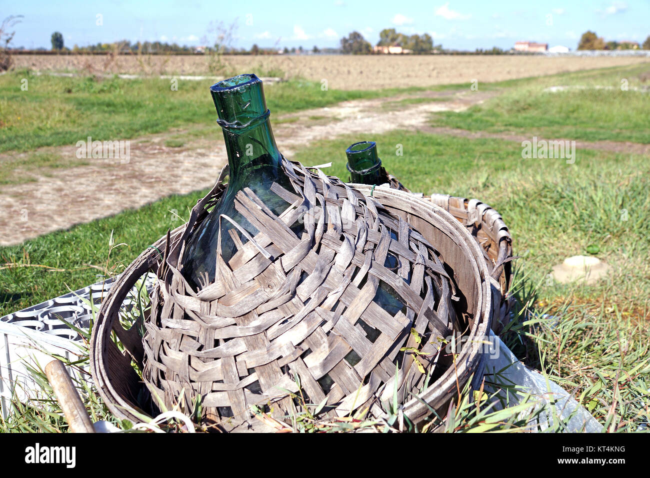 Ancien verre demijohn enveloppé dans l'osier abandonné Banque D'Images