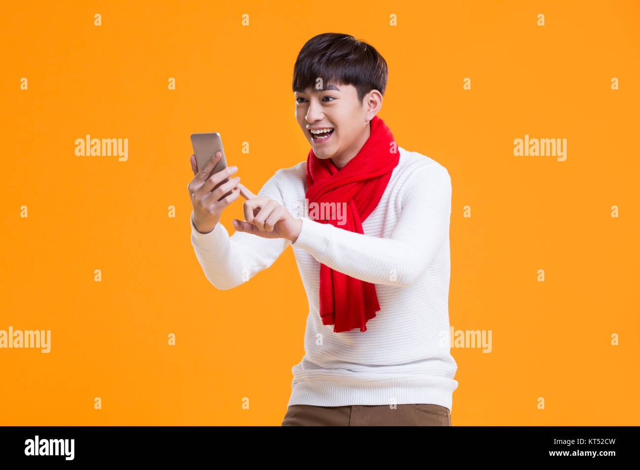 Cheerful young man grabbing Wechat hongbao avec smart phone Banque D'Images Cheerful young man grabbing Wechat hongbao avec smart phone Banque D'Images
