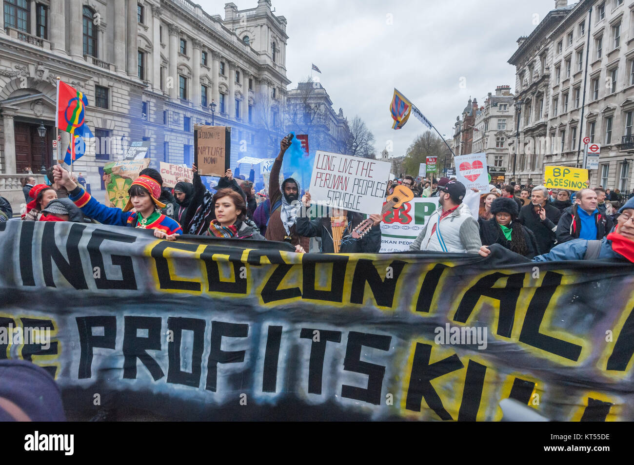 Un homme dans le bloc de première ligne mondiale détient une fumée bleue flare comme ils descendent Whitehall passé le ministère des Affaires étrangères et du Commonwealth sur le climat de Mars et emploi à Londres. Banque D'Images