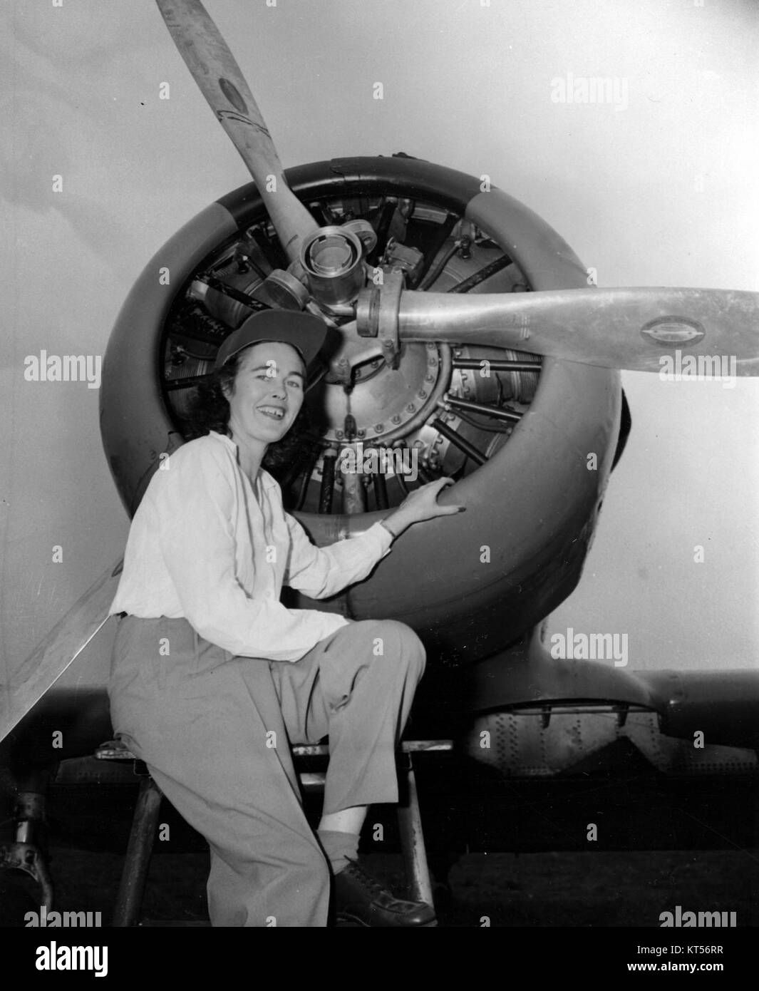 Une photographie de Nancy Corrigan, pionnière de l'aviation, debout à côté d'un moteur d'avion, capturant un moment dans l'histoire des débuts du vol et des femmes dans l'aviation. Banque D'Images