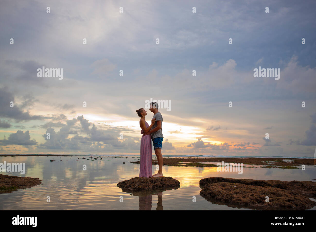 Beau couple Hugging pendant le coucher du soleil près de l'océan. De miel. Banque D'Images