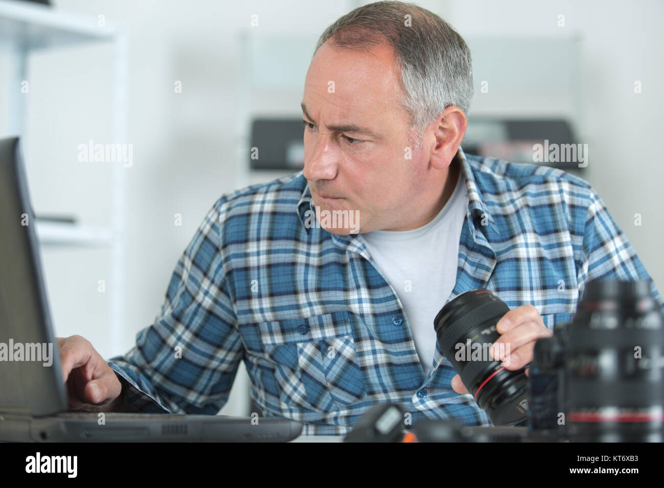 L'homme à l'aide de l'ordinateur portable et la tenue d'un appareil photo reflex numérique Banque D'Images